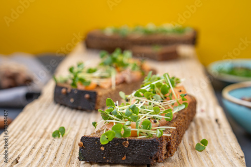 salmon toast with a grass (micro-green) wooden background top view. concept of healthy eating. assortment of bruschetta. bread with red fish.