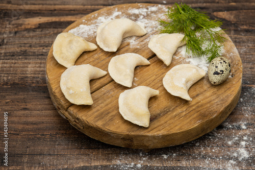 Frozen dumplings on a wooden plate on a wooden background