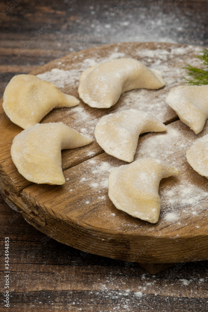 Frozen dumplings on a wooden plate on a wooden background