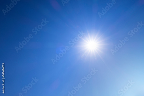 Abstract nature background of Beautiful sunny dark blue sky with bright sun shining with sunbeam, sunlight, sun rays & flares during midday at tropical summer or spring daylight sunshine day, space 