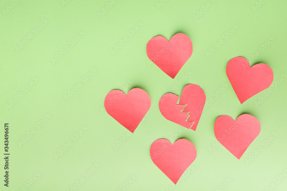 Paper hearts on a green background. one inside symbolizes breakup with someone, breakdown, depression