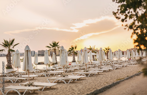 Fototapeta Naklejka Na Ścianę i Meble -  Beach chairs on the sandy beach and sea at summer sunset time.