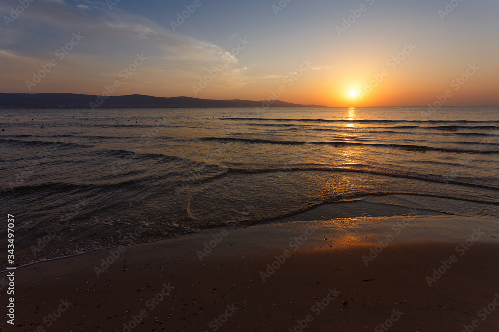 The sun sits behind the horizon. Summer landscape. Warm evening on the seashore.