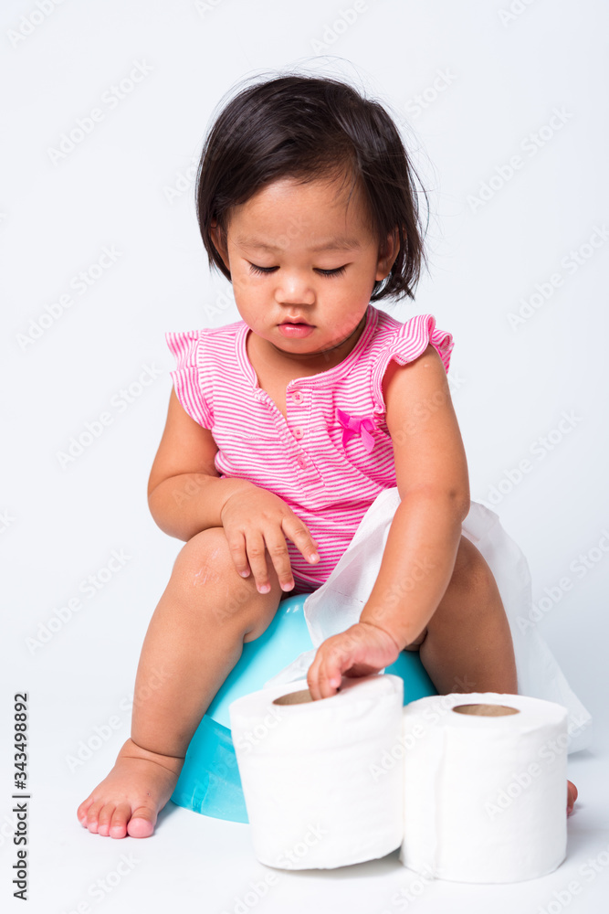 Asian little cute baby child girl education training to sitting on blue chamber pot or potty with toilet paper rolls, studio shot isolated on white background, wc toilet concept Asian little cute baby child girl education training to sitting on blue chamber pot or potty with toilet paper rolls, studio shot isolated on white background, wc toilet concept