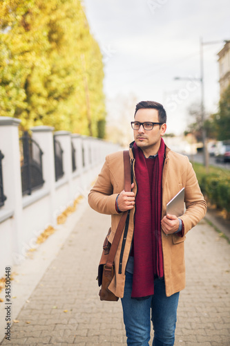 Businessman walking down the street holding tablet.