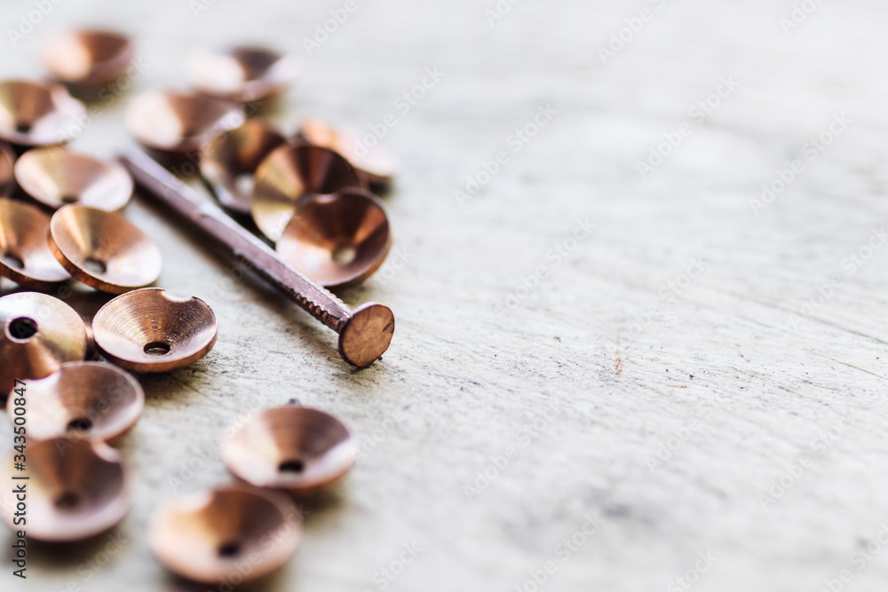 Shiny copper nails and rivets (roves) scattered on a white wooden surface Shiny copper nails and rivets (roves) scattered on a white wooden surface