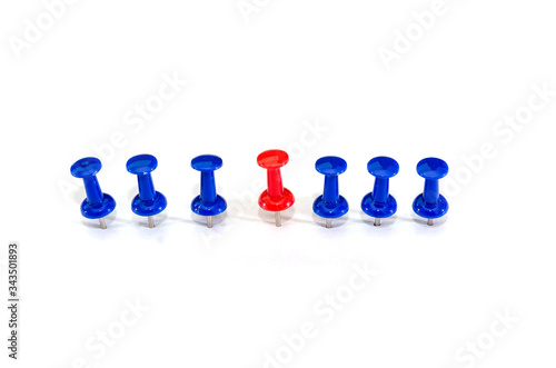 Red pin in the middle of blue pins on a white background. Stand out, think differently. individuality and leadership concept.