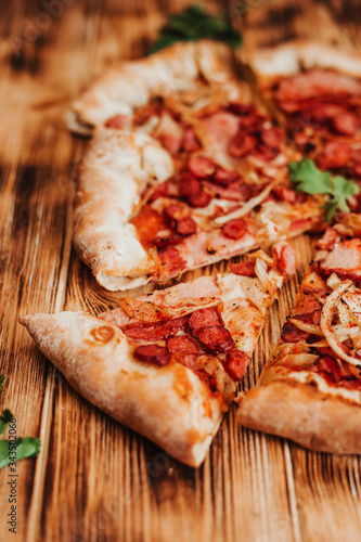 Clice of pizza with pepperoni and salami on a rustic wooden table. photo