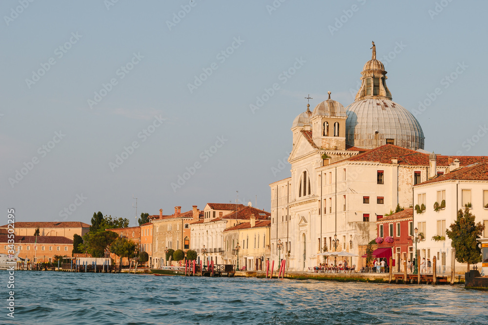 Street of Venice in summer time. Italian view. Roof, sea canal, boat in sunny day. Old city, ancient buildings.  Italy. Popular tourist destination of Italy. Church of St. Mary the Triumphant. Europe.
