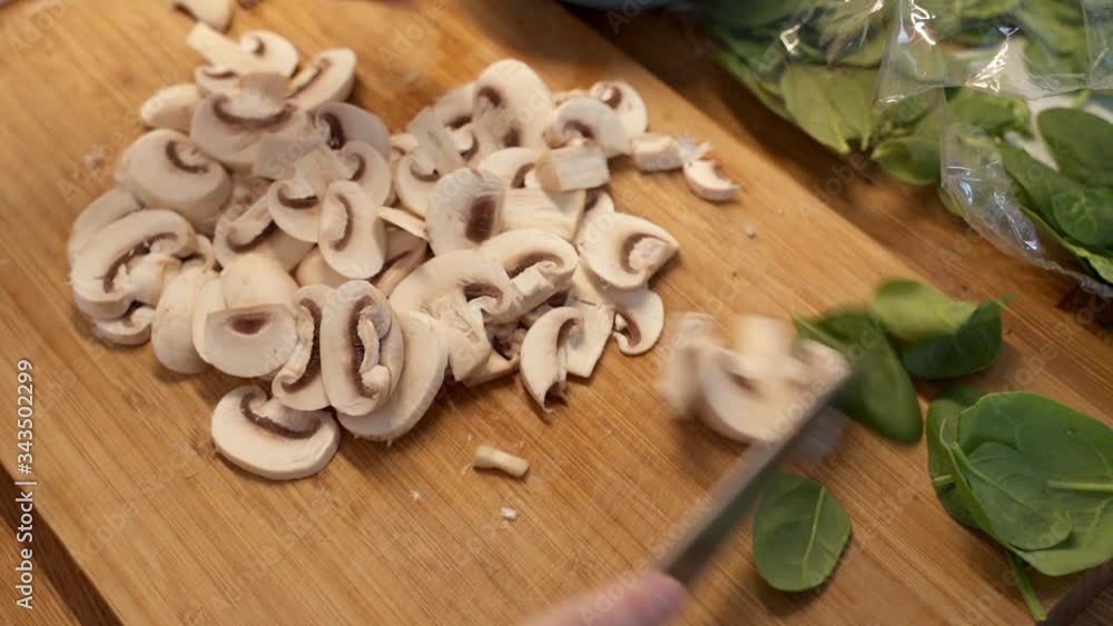 Woman cutting mushroom on table, close-up. Hands cutting mushrooms on a cutting board. Young woman cutting mushrooms in the kitchen. Woman cutting mushroom on table, close-up. Hands cutting mushrooms on a cutting board. Young woman cutting mushrooms in the kitchen.