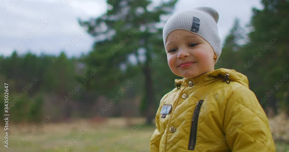 Slow motion happy boy close-up laughing and dreamy looking at the nature of the Park and the trees. A child who knows the world around him. Satisfied and admiring the baby in the woods. Slow motion happy boy close-up laughing and dreamy looking at the nature of the Park and the trees. A child who knows the world around him. Satisfied and admiring the baby in the woods.