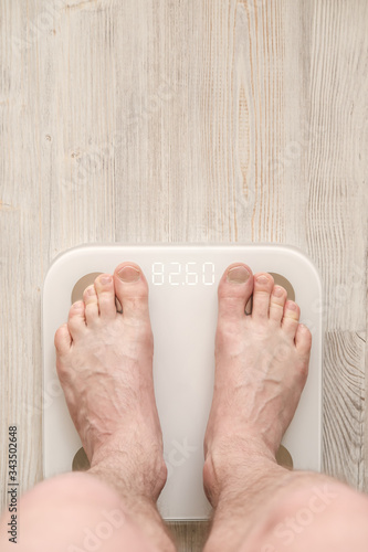 Male bare feet stand on smart scales that makes bioelectric impedance analysis, BIA, body fat measurement. Copy space.