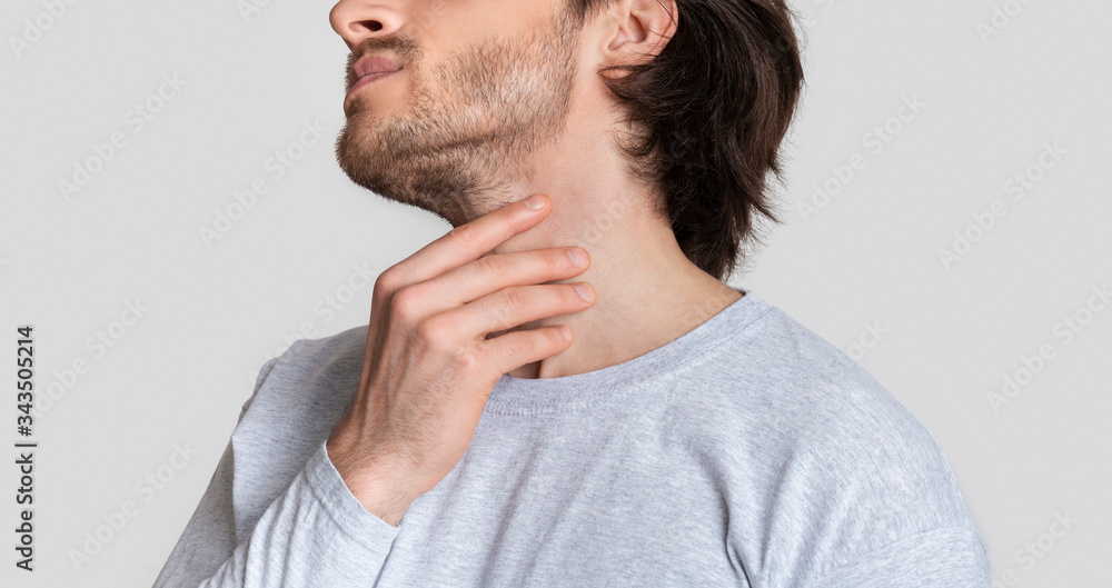 Man with throat sore is holding aching spot Man with throat sore is holding aching spot
