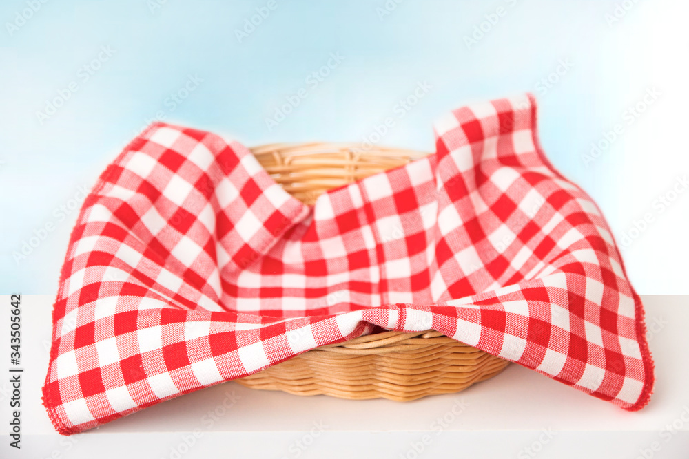Wicker basket with a red checkered cloth inside on a white tablenapkin
Wicker basket with a red checkered cloth inside on a white tablenapkin