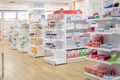 Medicines arranged in shelves, Pharmacy drugstore retail Interior blur abstract background with medicine healthcare product on glass cabinet with neon light. © kamol