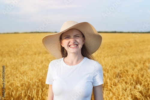 Portrait of pretty funny woman in hat on background of wheat field.