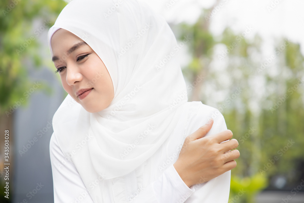 woman with shoulder or neck pain; portrait of muslim woman suffering from shoulder or neck pain, stiffness, injury, chronic bone or muscle injury concept; young adult Islamic woman health care model woman with shoulder or neck pain; portrait of muslim woman suffering from shoulder or neck pain, stiffness, injury, chronic bone or muscle injury concept; young adult Islamic woman health care model