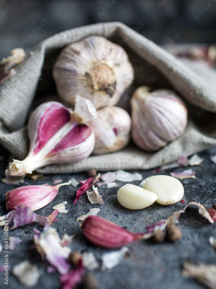 Garlic banner. Garlic bulbs on wooden rustic table. Focus on a bunch of peeled garlic cloves.