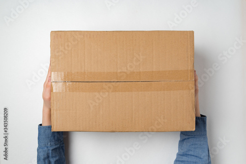 Hands holding large cardboard box. Delivery of parcels to house concept. Top view.