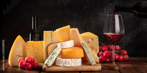 Valokuva Cheese panorama, mvarious cheeses with grapes and pouring wine, a side view on a
