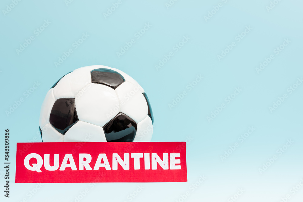 football near paper with quarantine lettering on blue football near paper with quarantine lettering on blue