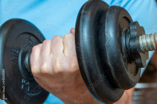 dumbbell in the man hand doing fitness sport exercise at home close up