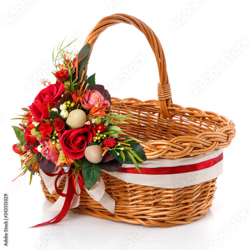 Brown wicker basket with original handle. Decor with flowers  eggs and ribbons. Isolated on a white background