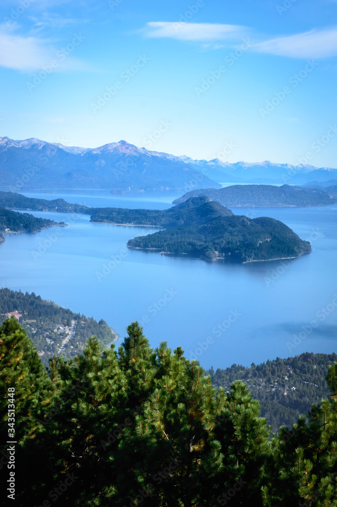 Landscape with lakes between mountains and pine trees. On top of a mountain in Bariloche, Argentina. A sunny summer day.