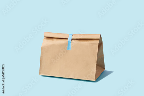 Brown clear empty blank paper bag for food delivery on blue background with copy space. Packaging template mock up fast food.