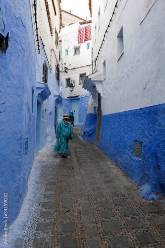 Unrecognized women walking down the ancient street in kasbah - old part of city Chefchaouen, Morocco. © leospek