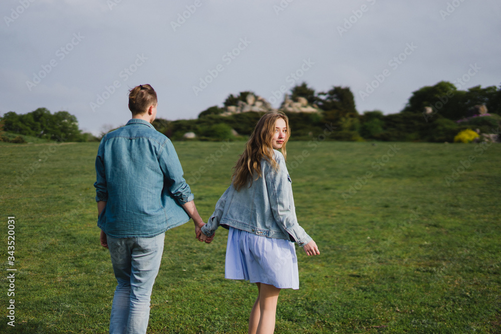 Romantic and happy caucasian couple in casual clothes hugging on the background of beautiful blooming trees. Love, relationships, romance, happiness concept. Man and woman walking outdoors together. Romantic and happy caucasian couple in casual clothes hugging on the background of beautiful blooming trees. Love, relationships, romance, happiness concept. Man and woman walking outdoors together.