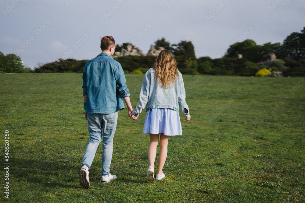 Romantic and happy caucasian couple in casual clothes hugging on the background of beautiful blooming trees. Love, relationships, romance, happiness concept. Man and woman walking outdoors together. Romantic and happy caucasian couple in casual clothes hugging on the background of beautiful blooming trees. Love, relationships, romance, happiness concept. Man and woman walking outdoors together.