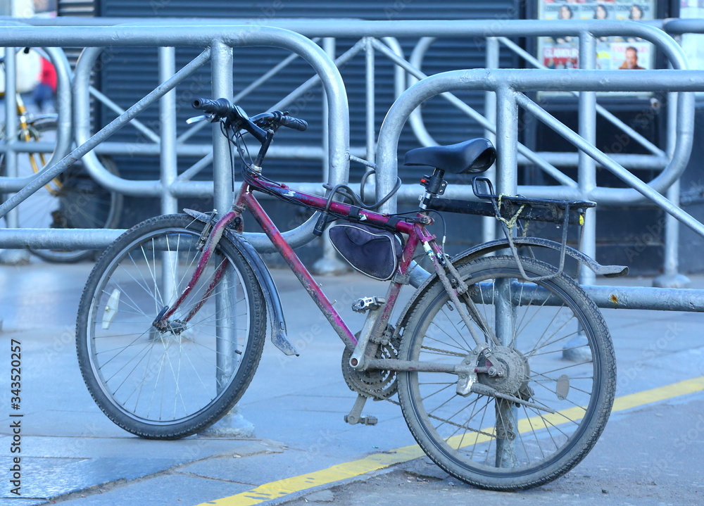 An old dirty bike is strapped to the divider barrier at the metro station