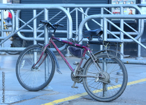 An old dirty bike is strapped to the divider barrier at the metro station