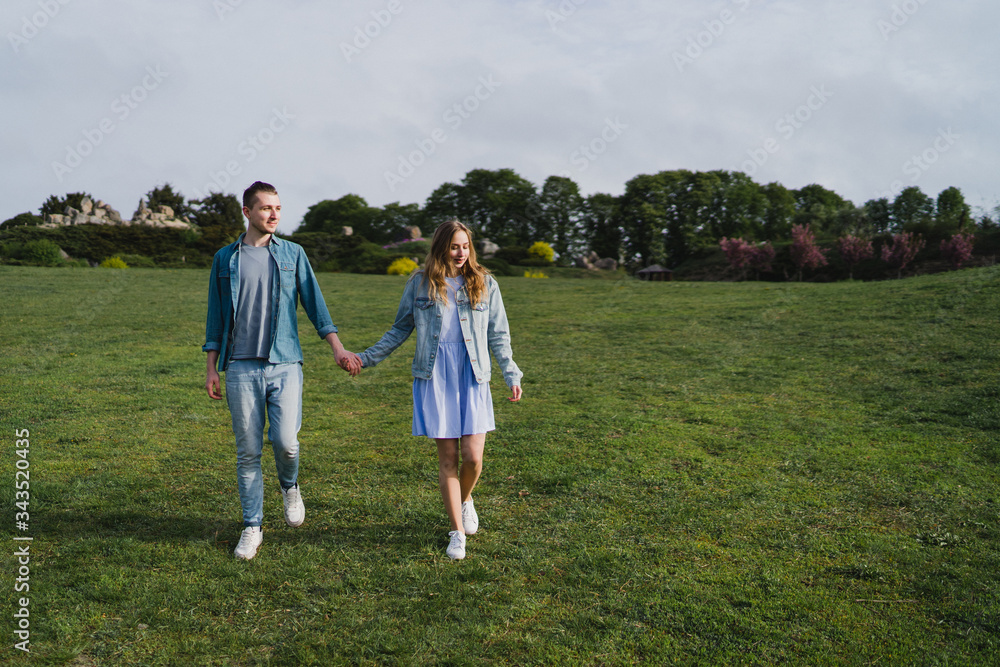 Romantic and happy caucasian couple in casual clothes hugging on the background of beautiful blooming trees. Love, relationships, romance, happiness concept. Man and woman walking outdoors together. Romantic and happy caucasian couple in casual clothes hugging on the background of beautiful blooming trees. Love, relationships, romance, happiness concept. Man and woman walking outdoors together.