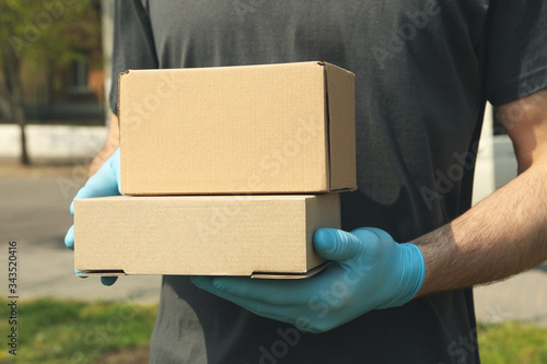 Delivery man in gloves holds blank boxes, space for text