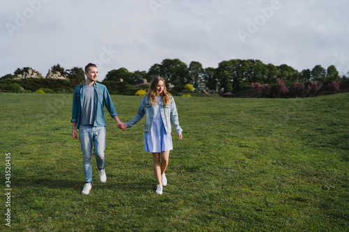 Romantic and happy caucasian couple in casual clothes hugging on the background of beautiful blooming trees. Love, relationships, romance, happiness concept. Man and woman walking outdoors together.