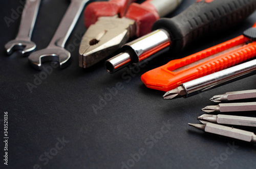 A Set of a lot of different red tools for working include hammer wrench bit pliers, screwdriver, paper knife, screwdriver nozzle, key on black background 