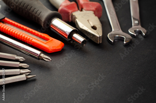 A Set of a lot of different red tools for working include hammer wrench bit pliers, screwdriver, paper knife, screwdriver nozzle, key on black background 