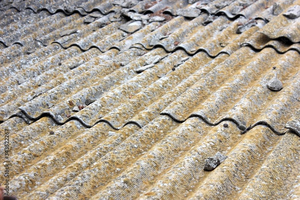 Old slate covered with moss and lichen. The roof of the old house. Slate with traces of operation.