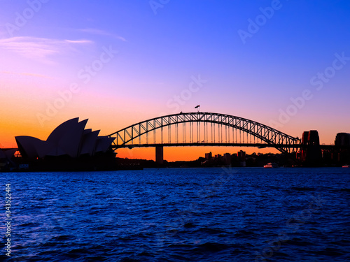 Fototapeta Naklejka Na Ścianę i Meble -  Panoramic view of Sydney Harbour with all the vibrant colours on a orange and blue sunset afternoon 