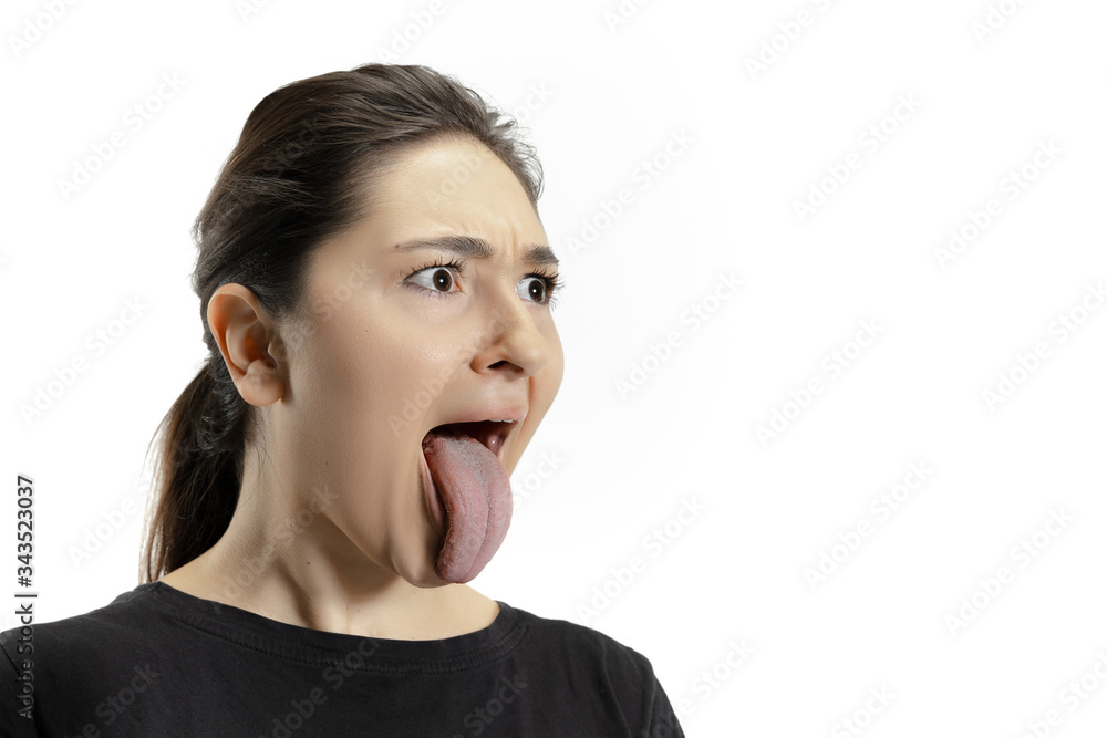 Smiling girl opening her mouth and showing the long big giant tongue isolated on white background. Looks shocked, attracted, wondered and astonished. Copyspace for ad. Human emotions, marketing.