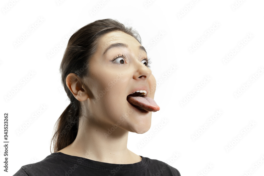 Smiling girl opening her mouth and showing the long big giant tongue isolated on white background. Looks shocked, attracted, wondered and astonished. Copyspace for ad. Human emotions, marketing. Smiling girl opening her mouth and showing the long big giant tongue isolated on white background. Looks shocked, attracted, wondered and astonished. Copyspace for ad. Human emotions, marketing.