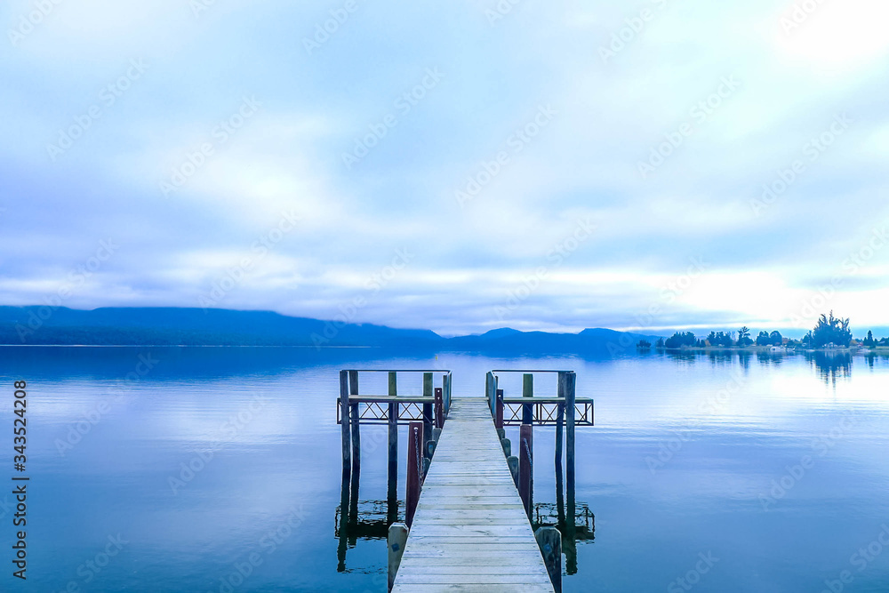 Naklejka premium wooden pier at a lake in a dark cloudy atmosphere