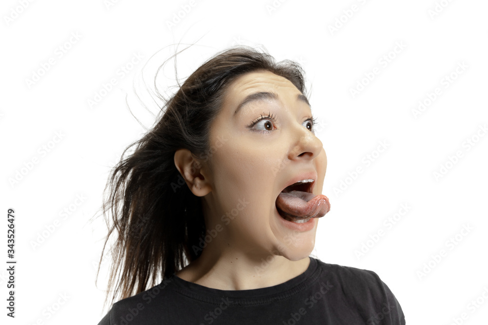 Smiling girl opening her mouth and showing the long big giant tongue isolated on white background. Looks shocked, attracted, wondered and astonished. Copyspace for ad. Human emotions, marketing. Smiling girl opening her mouth and showing the long big giant tongue isolated on white background. Looks shocked, attracted, wondered and astonished. Copyspace for ad. Human emotions, marketing.