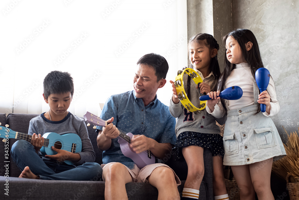 Father play music with young daughter and sone at living room,relax time,family activity