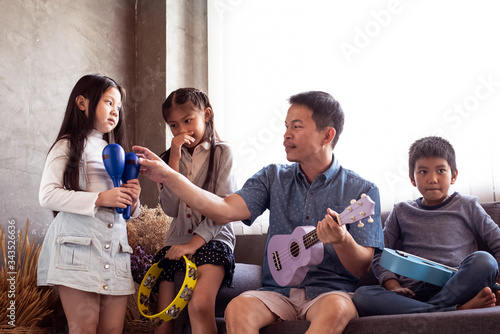 Father play music with young daughter and sone at living room,relax time,family activity