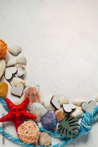 Summer background. Different types of seashells, rope on wooden background.