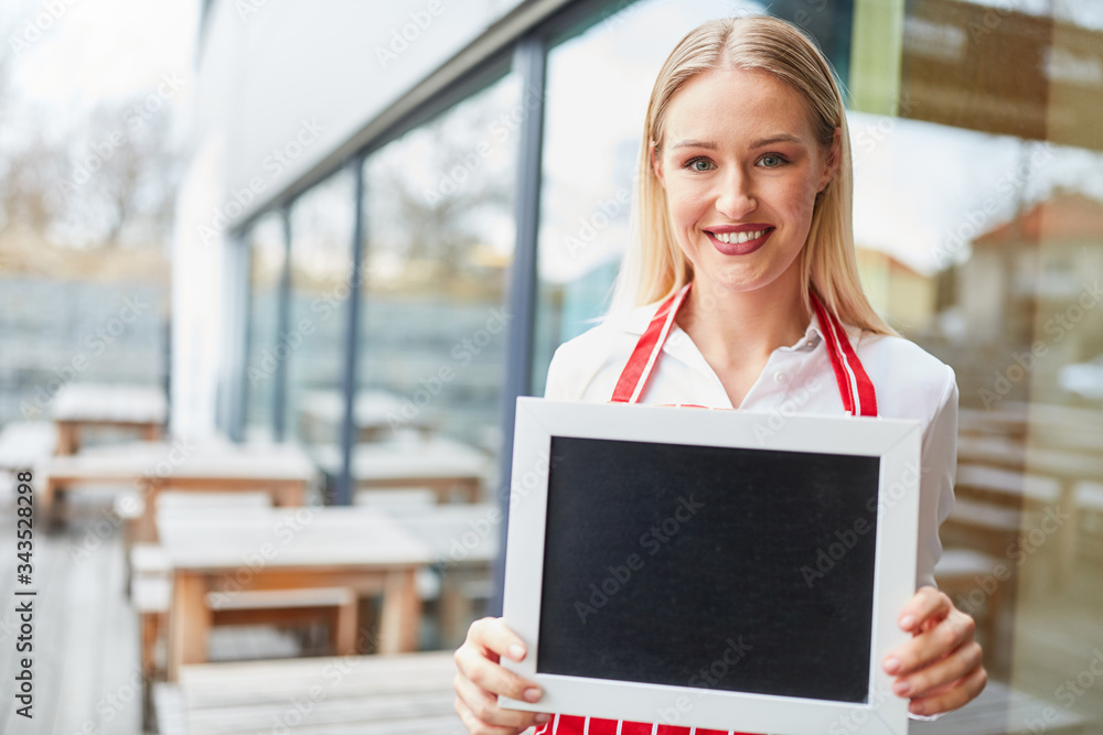 Waitress in front of restaurant holds blank chalkboard Waitress in front of restaurant holds blank chalkboard