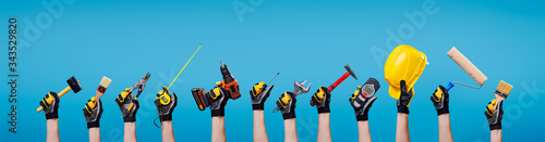 Fotografie, Obraz Workers hands with different tools on empty blue background